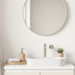 Warm minimalist Japandi small bathroom with a light-oak over-toilet shelf and rolled cream towels.
