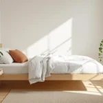 Warm minimalist Japandi small bedroom with a low light-oak bed and cream bedding.
